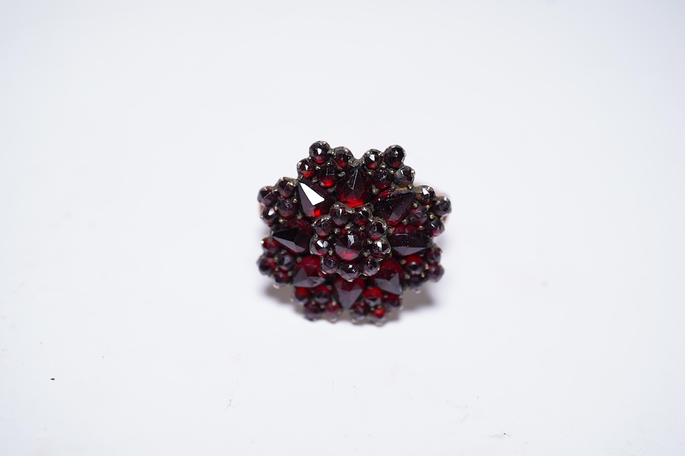 A suite of garnet and paste jewellery, comprising: a brooch, 5cm diameter; a bangle, inner circumference 16cm; two rings, sizes I and M; a pair of earrings, and a single earring, each set with rose-cut garnets; and a pai